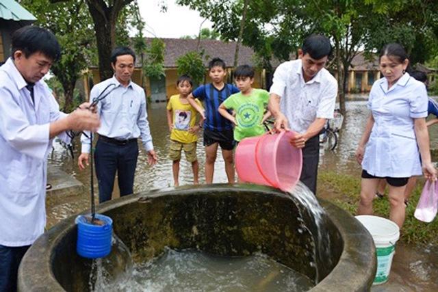 Cán bộ y tế hỗ trợ và hướng dẫn người dân làm sạch nguồn nước công cộng