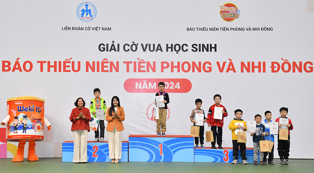 Nhà báo Đỗ Thị Thanh Bình - Phó Tổng Biên tập Báo TNTP&NĐ (bìa trái) và bà Đinh Thị Huyền Trang - đại diện nhãn hàng Weki IQ trao giải cho các kỳ thủ xuất sắc khối lớp 2-3, bảng Nâng cao