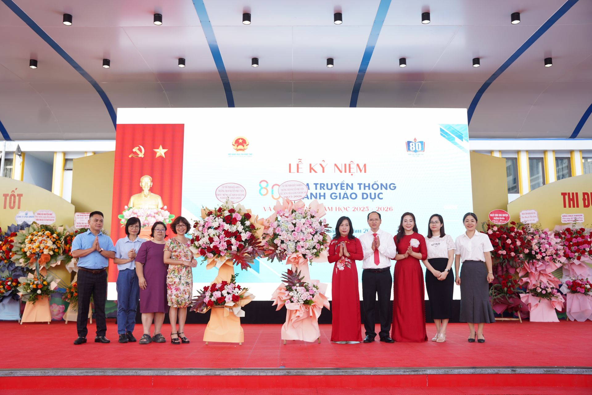 Ban Giám hiệu nhà trường nhận hoa chúc mừng từ đại biểu, khách mời.