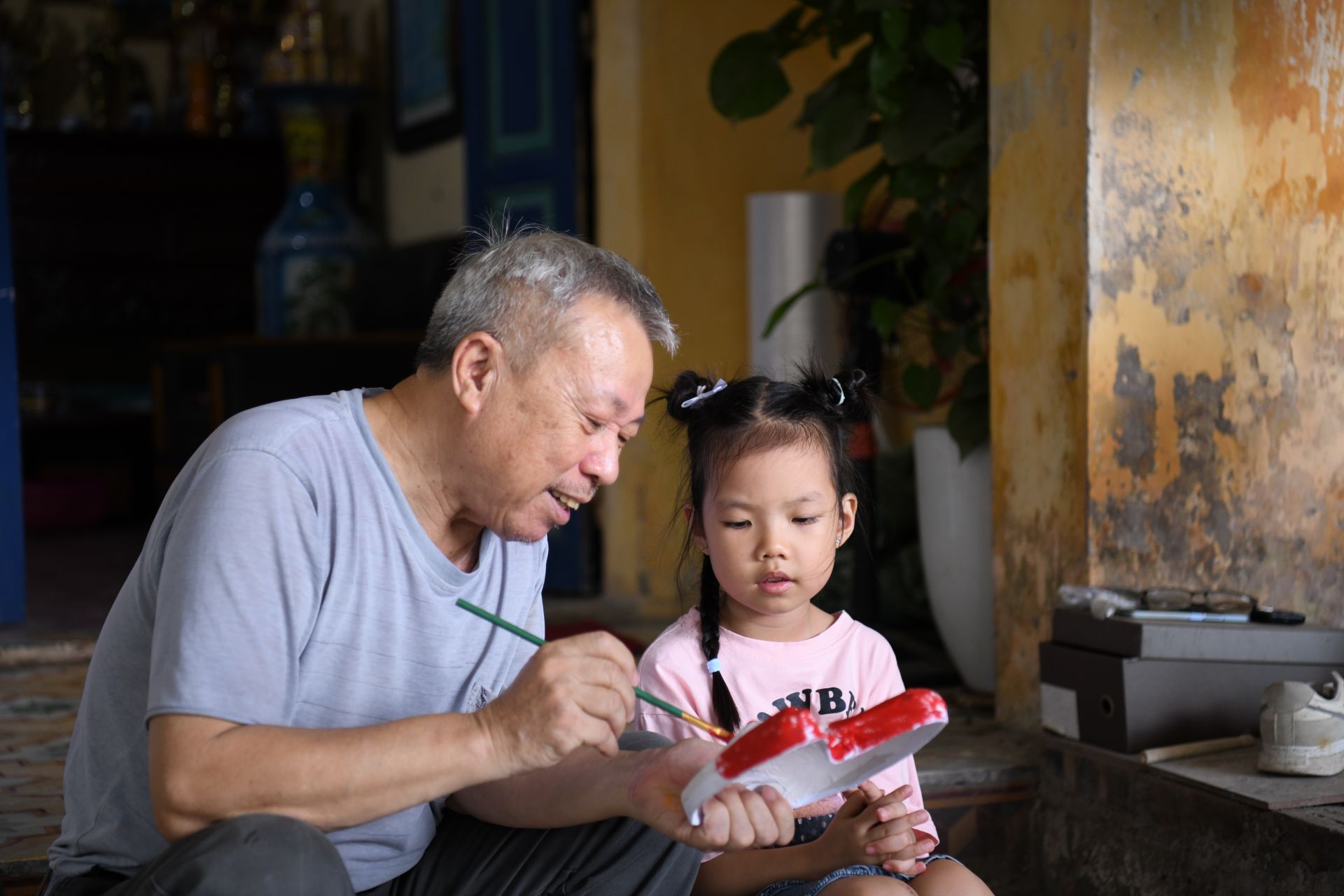 Khoảnh khắc ấm áp: bác Đông hướng dẫn bé gái tô màu, truyền lửa nghề cho thế hệ mai sau.