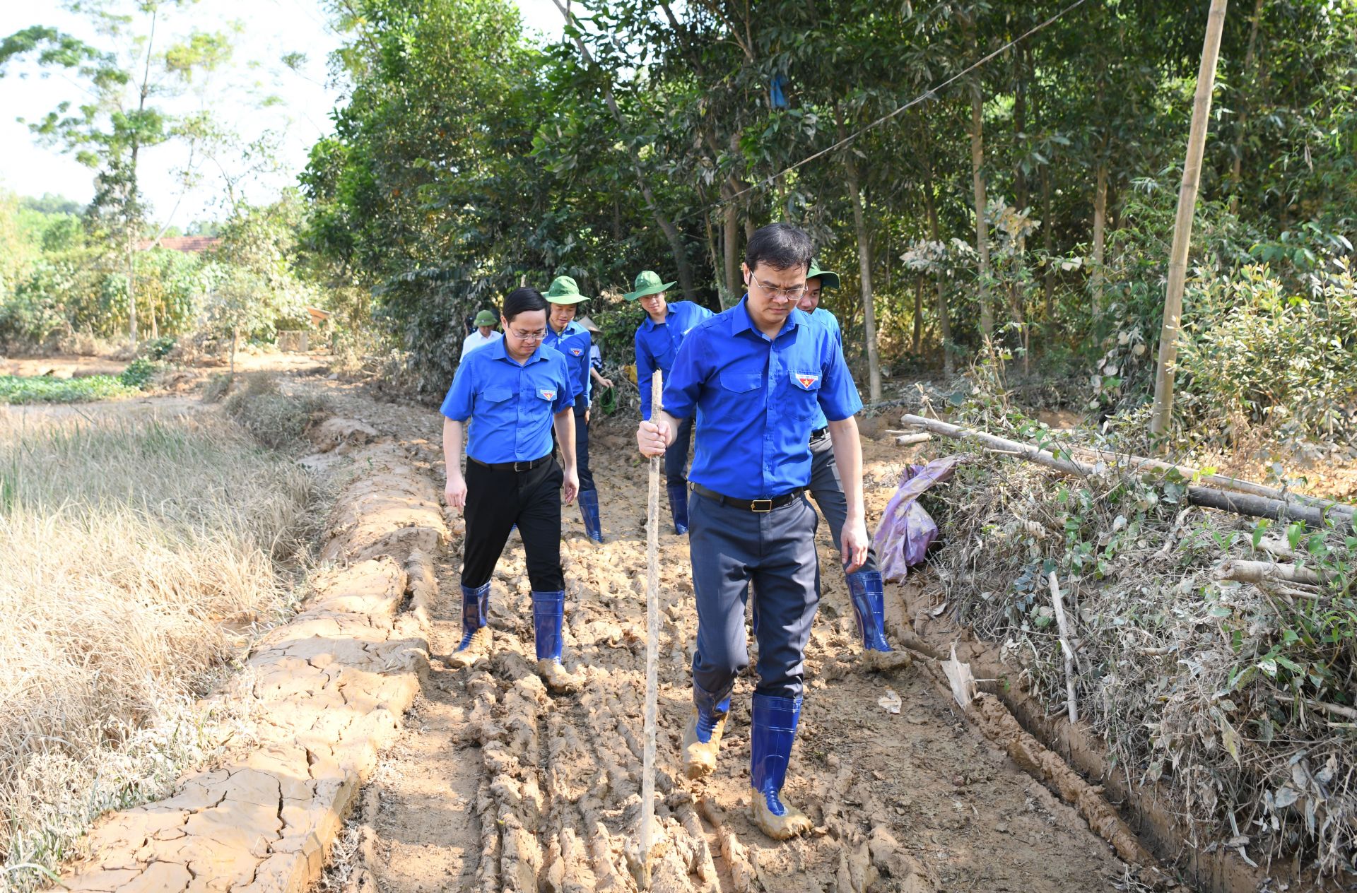 Đoàn công tác đi qua con đường bùn đất lầy lội để thăm hỏi và động viên gia đình em Nông Bảo An.