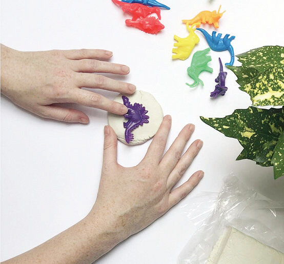 Bước 4: Đặt chú khủng
long đồ chơi vào giữa miếng
đất sét đã cán mỏng và ấn
xuống. Bạn nhớ ấn đều tay
và ấn lần lượt từng bộ phận
(đầu, chân và đuôi khủng
long) để hình in được rõ
ràng và sắc nét.