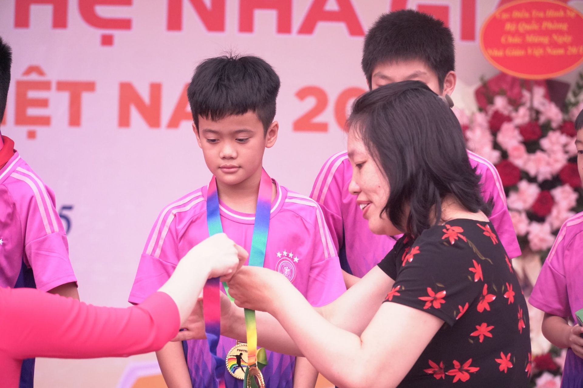 Bác Nguyễn Thị Vân, Trưởng ban đại diện Hội cha mẹ học sinh nhà trường, trao huy chương cho đội bóng đá vô địch.