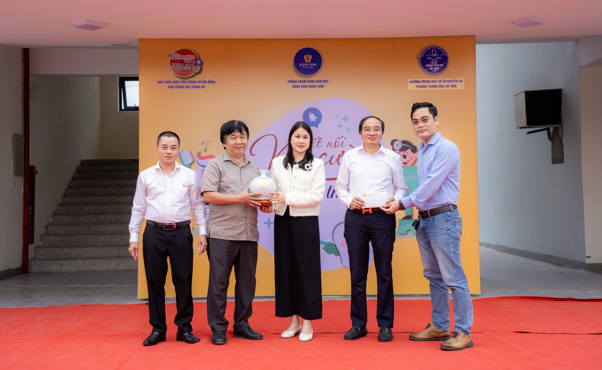 Nhà báo Phan Việt Hùng – Phó Tổng Biên tập Báo Thiếu niên Tiền phong và Nhi đồng trao quà cho Ban Giám hiệu nhà trường và Thach sĩ, bác sĩ Nguyễn Tất Tuấn – Phòng khám Nha khoa Răng Xinh trao tặng 7 Voucher điều trị răng chuyên sâu cho các thầy cô giáo