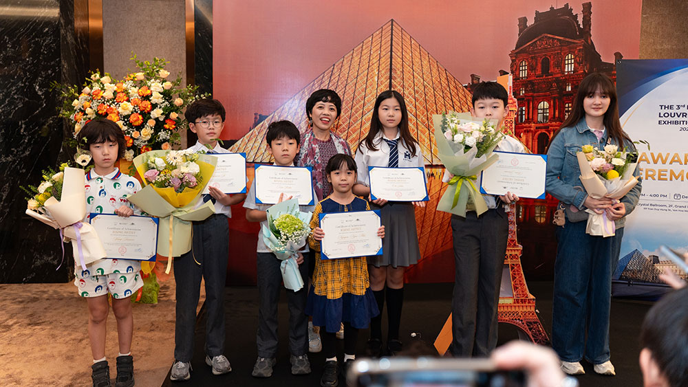 Thí sinh và người thân chụp ảnh lưu niệm tại khu vực check-in với hình ảnh Bảo tàng Louvre.