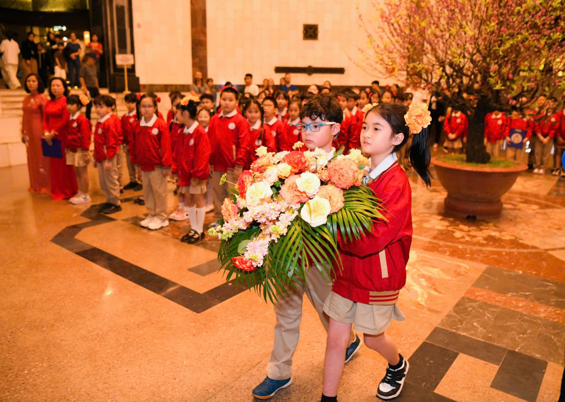 C&aacute;c bạn học sinh khối 3 d&acirc;ng hoa l&ecirc;n Chủ tịch Hồ Ch&iacute; Minh.