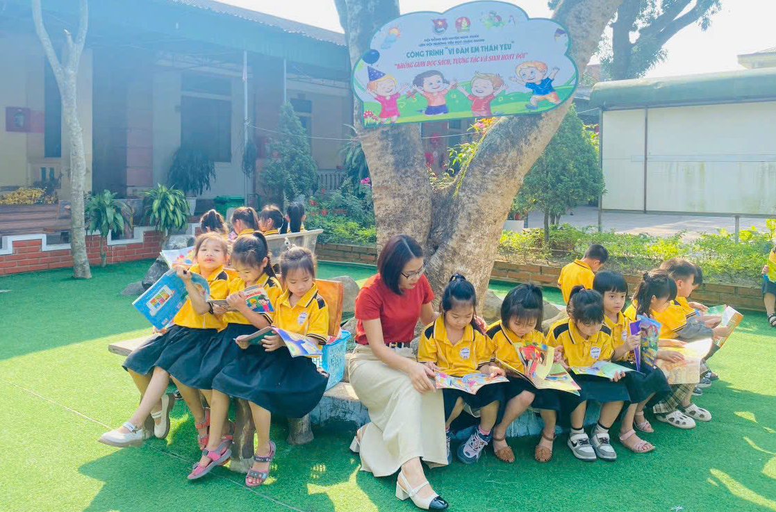 Niềm vui đọc b&aacute;o Đội của c&aacute;c em học sinh trong kh&ocirc;ng gian xanh m&aacute;t tại s&acirc;n trường
