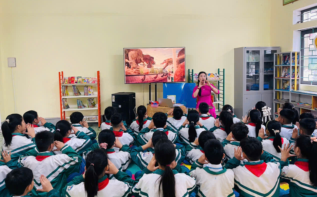 Tiết học đọc s&aacute;ch đầy hứng th&uacute; của c&aacute;c em học sinh tiểu học. Dưới sự hướng dẫn sinh động của c&ocirc; gi&aacute;o, c&aacute;c em chăm ch&uacute; lắng nghe v&agrave; tham gia tương t&aacute;c, kh&aacute;m ph&aacute; thế giới tri thức qua từng trang s&aacute;ch.