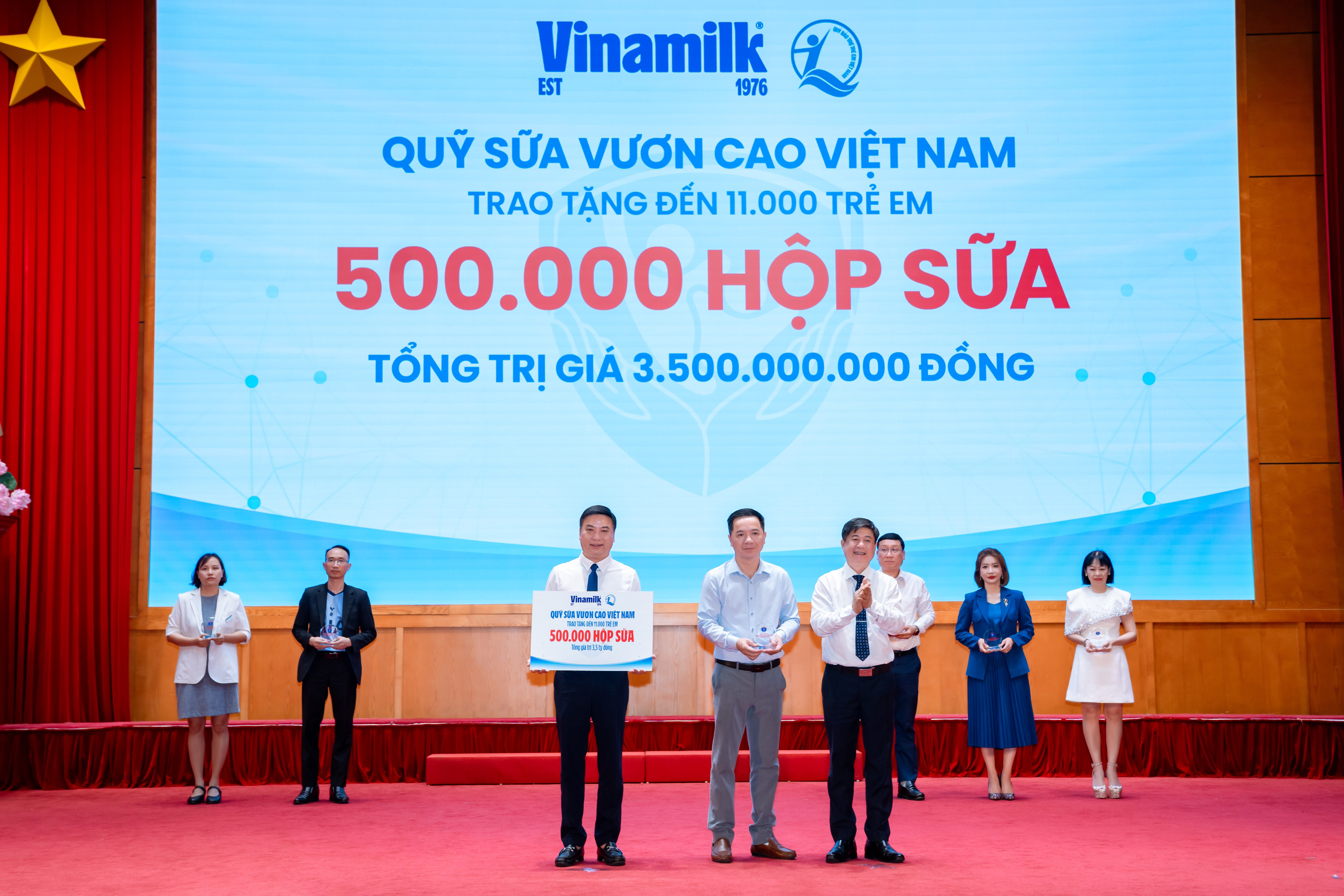 Đại diện Vinamilk (đứng giữa) trao bảng tượng trưng 500.000 hộp sữa v&agrave; nhận kỷ niệm chương từ Bộ Y tế.